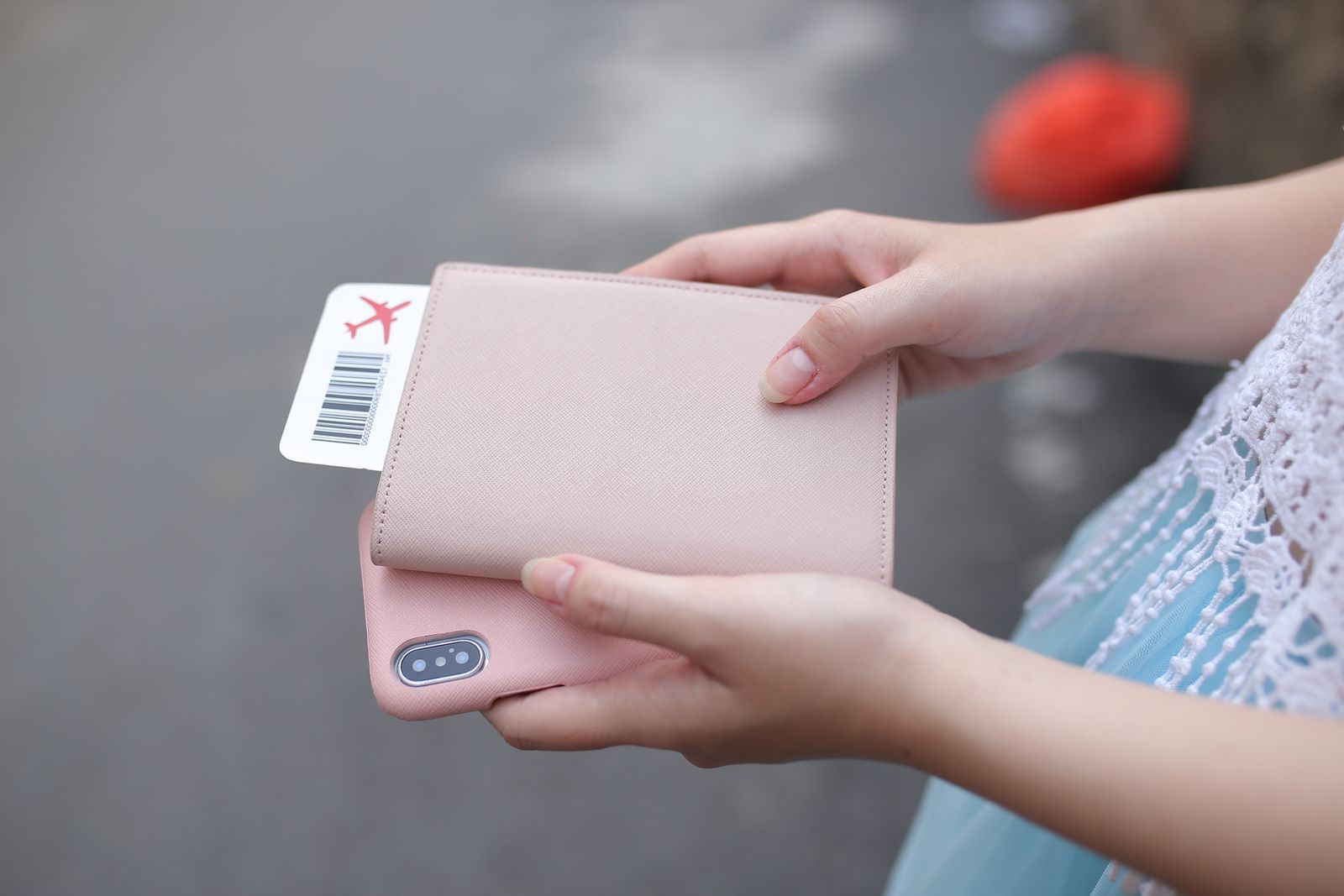 A traveler holding a pink passport wallet with a boarding pass tucked inside